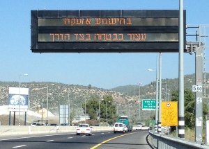 Highway sign says, "in case of air raid siren, safely go off highway and stop," because of Hamas rockets.